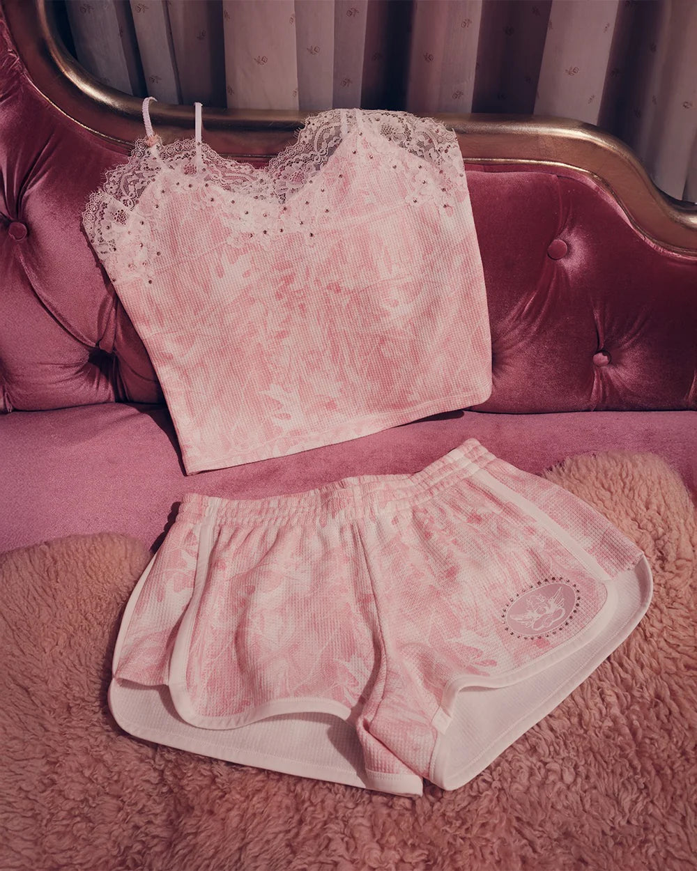 Pink lace top and shorts set on a pink couch with a patterned curtain in the background.