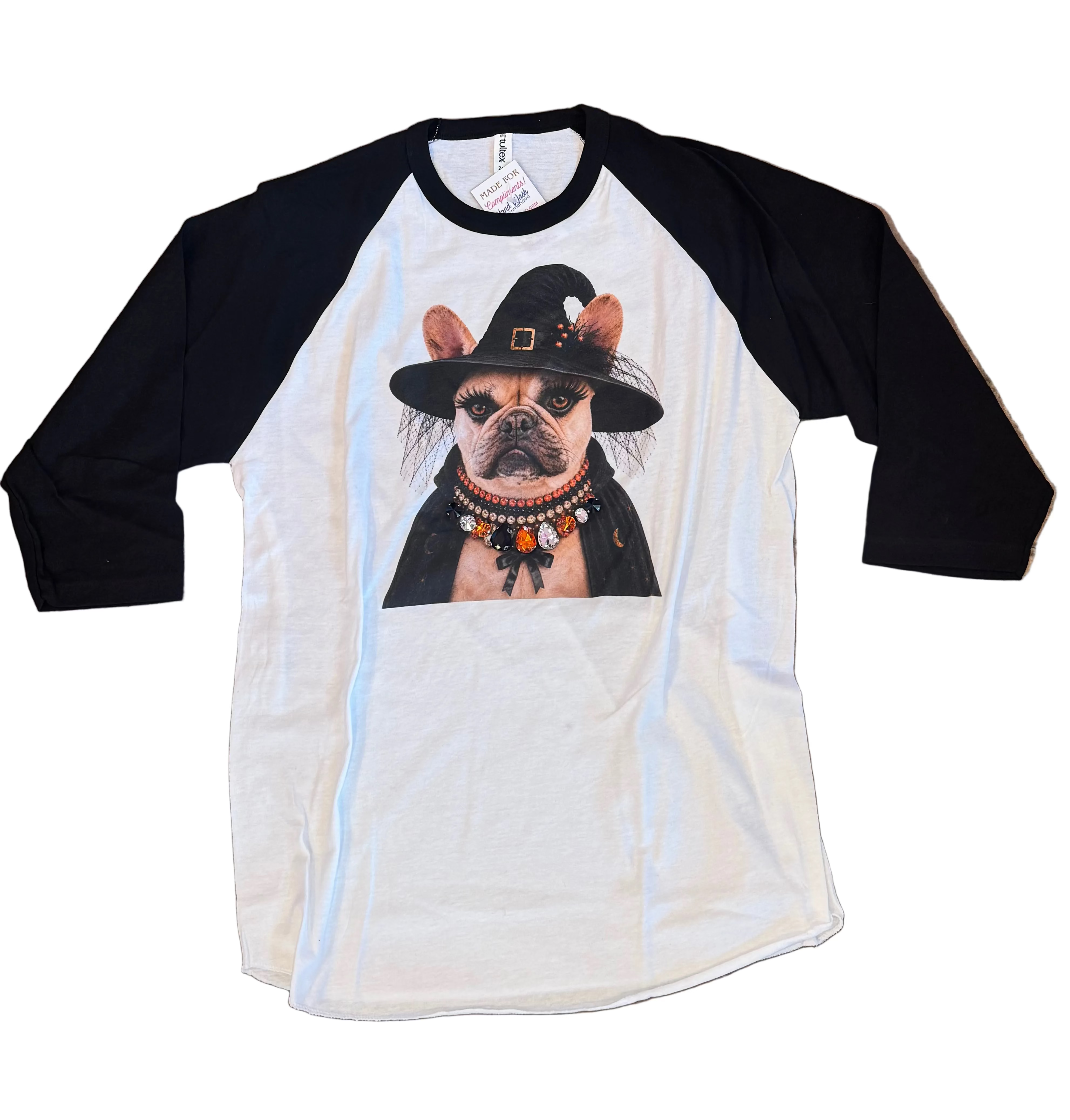 A white and black raglan baseball t-shirt featuring a graphic print of a French Bulldog dressed as a witch, wearing a bling crystal collar